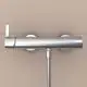 Chromene Brausearmatur an einer Wand, installiert mit zwei runden, silbernen Wandhaltern, von der Marke Ideal Standard.